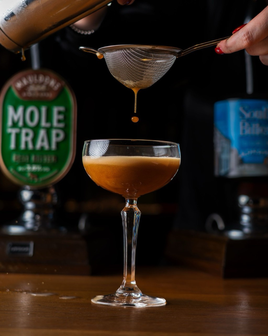 A cocktail being strained at the bar at The Peacock Inn