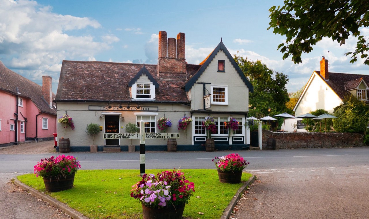 The timber-framed front of The Peacock Inn today, hung with flower baskets, in the village of Chelsworth