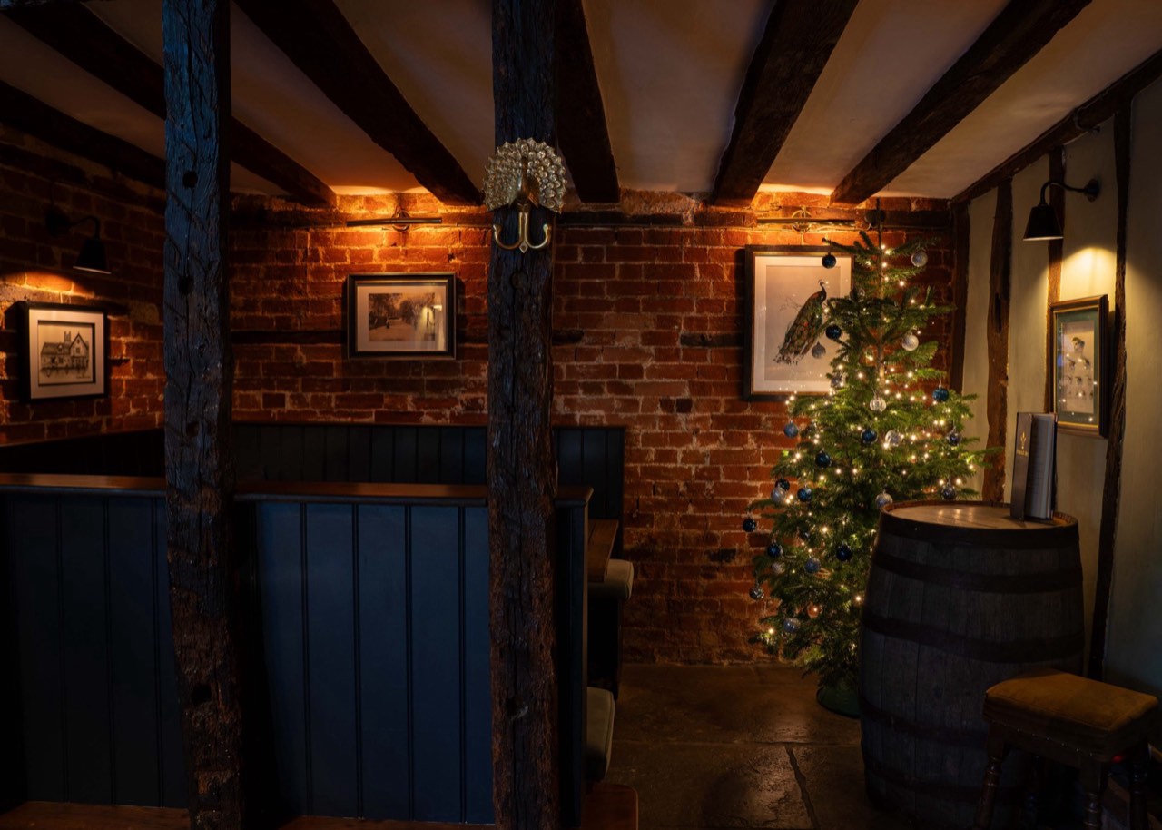 A candlelit, beamed dining room laid for a private celebration at The Peacock Inn