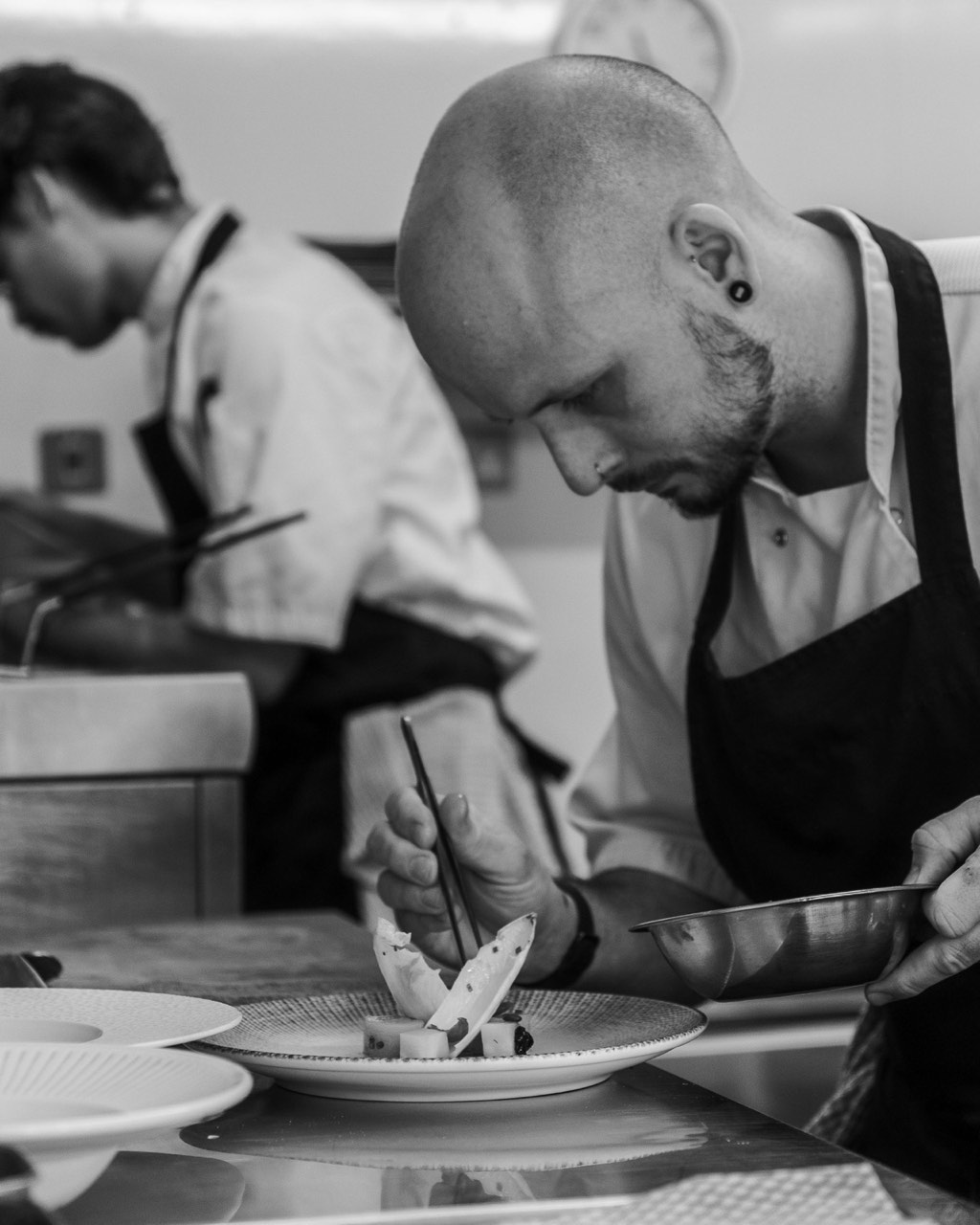 Black-and-white photograph of hands at work in the kitchen at The Peacock Inn