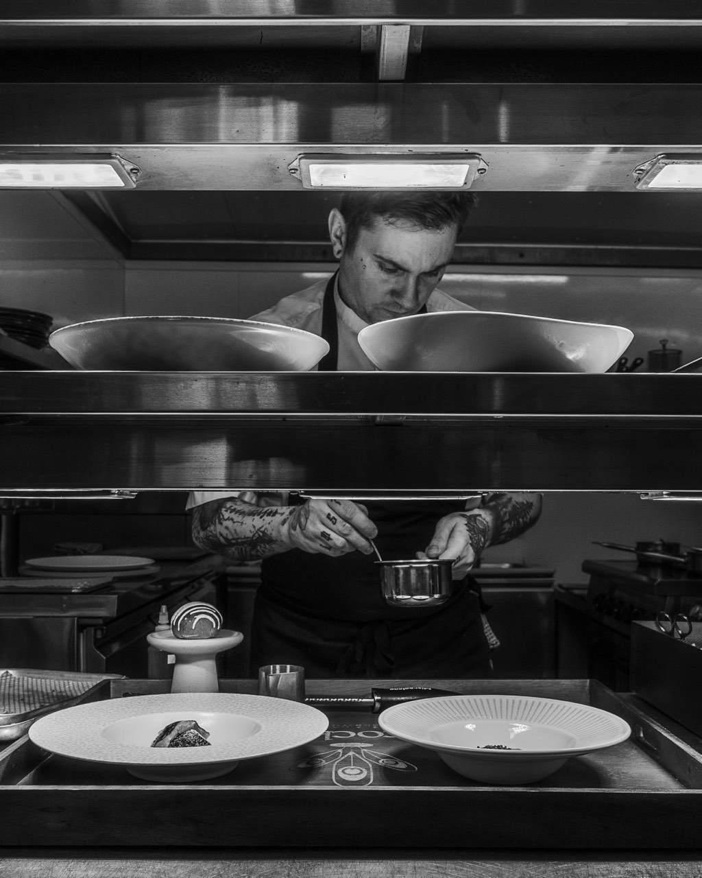 Black-and-white photograph of the kitchen at The Peacock Inn during evening service